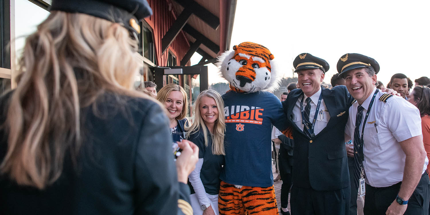 United aviate instructor and students posing for picture with Auburn University mascot
