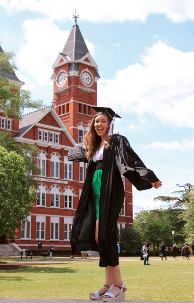Andrea Moore posing in front of Auburn at graduation