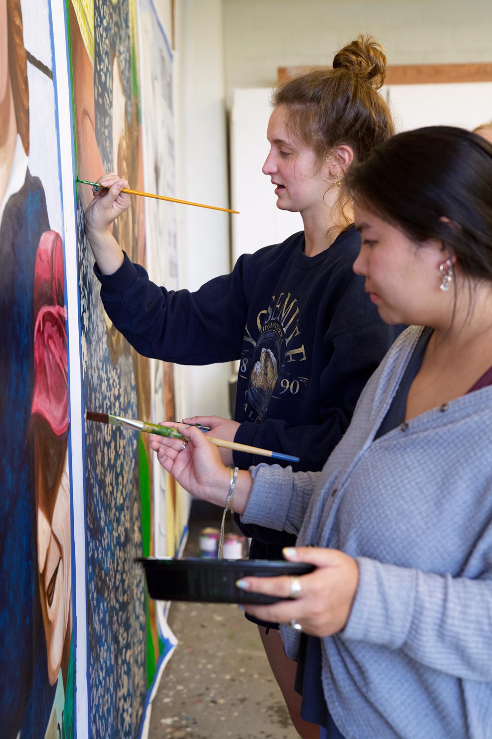 Two female art students painting mural