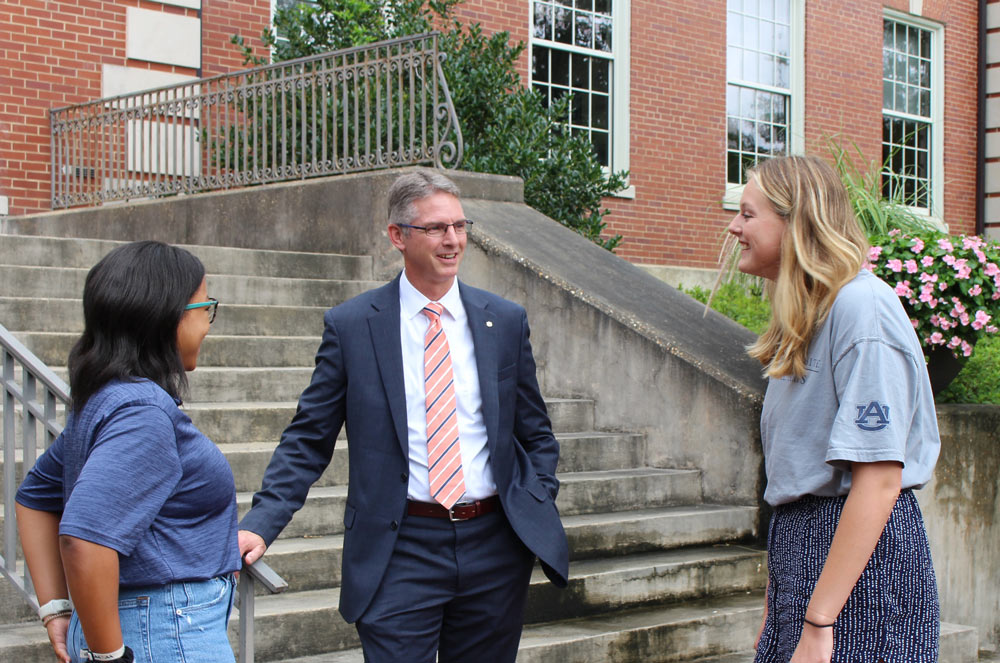 Dean Jason Hicks talking with two students on steps