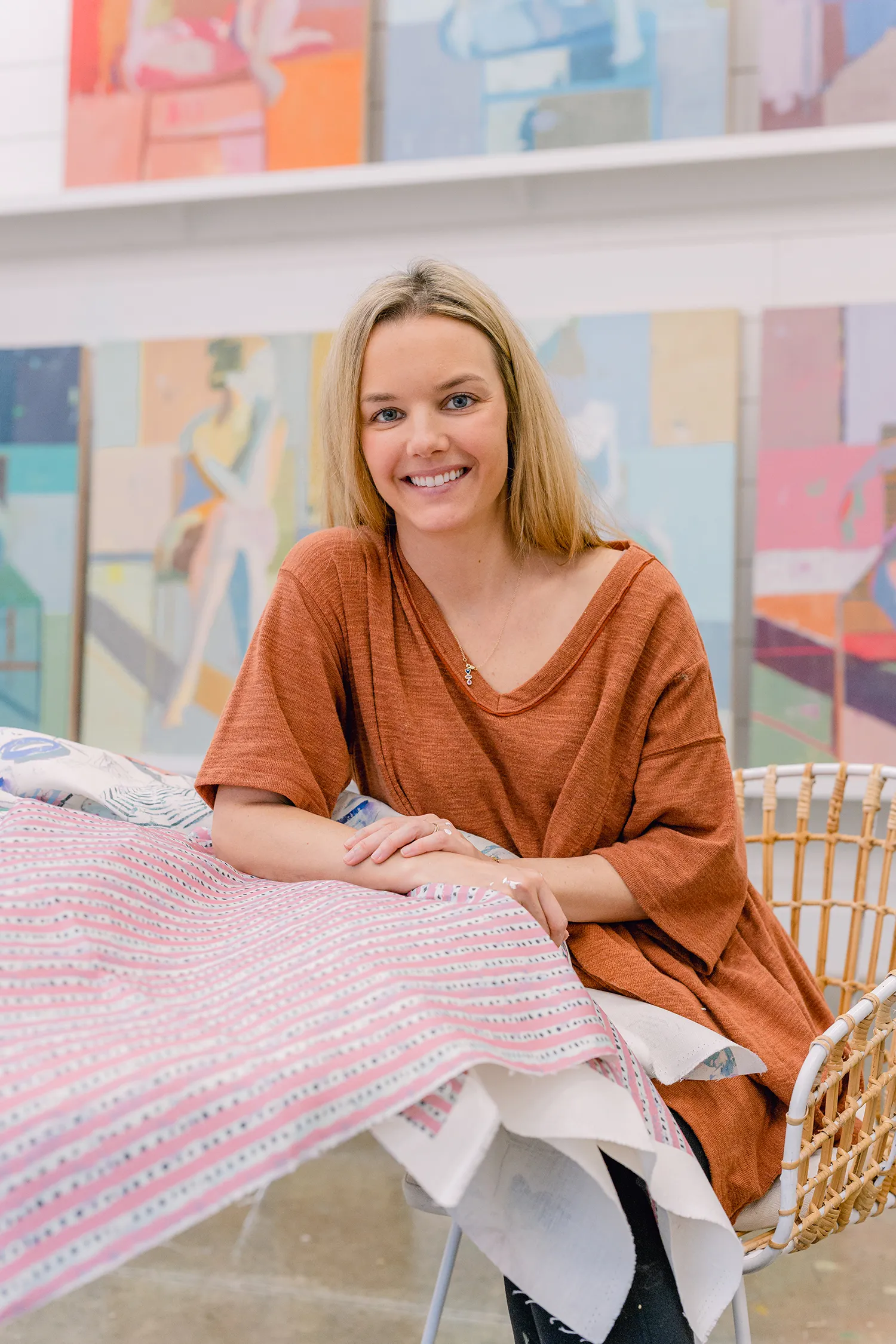 Teil Henly smiling in front of paintings with textiles