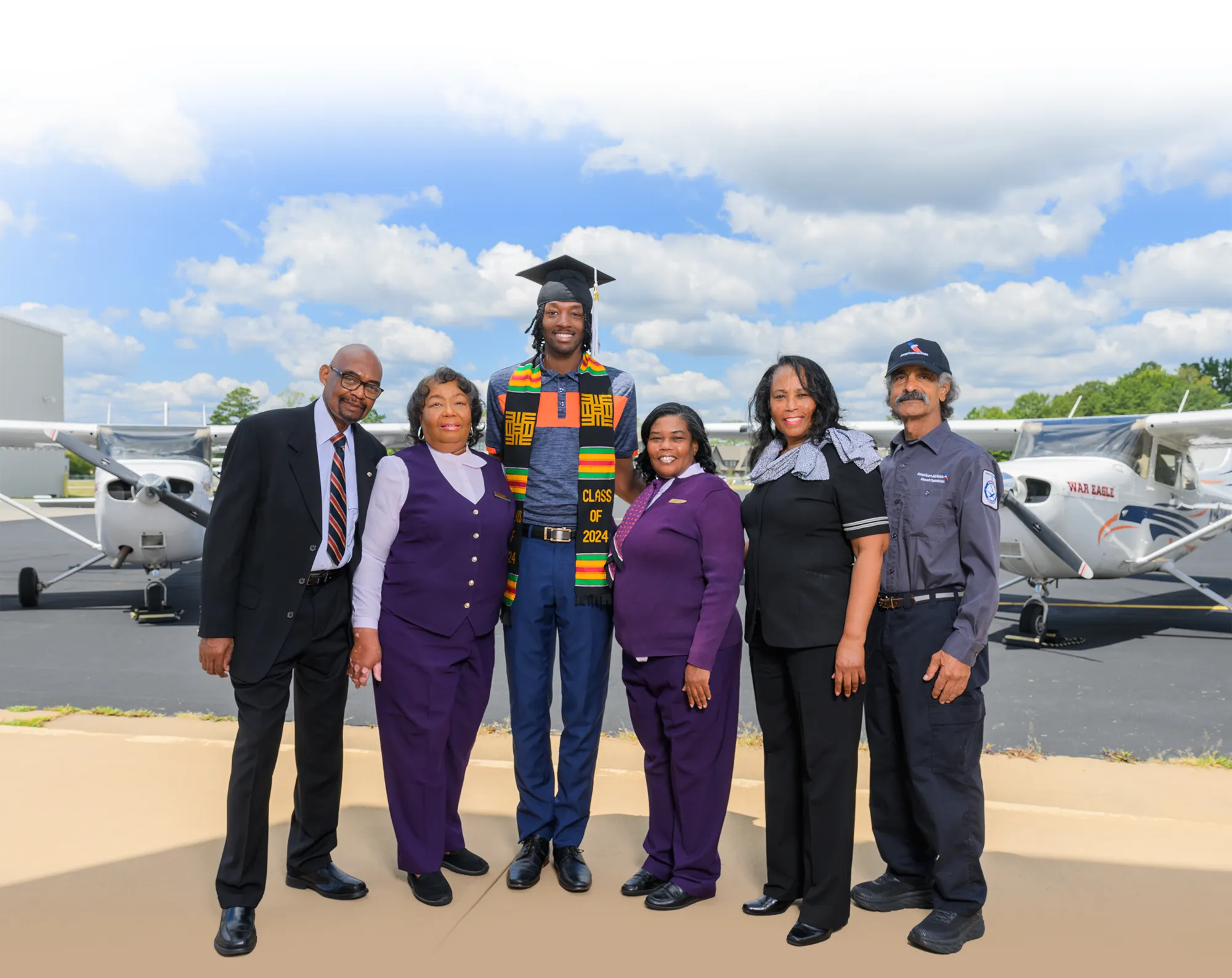 Sims family wearing airline uniforms in front of Auburn airplanes