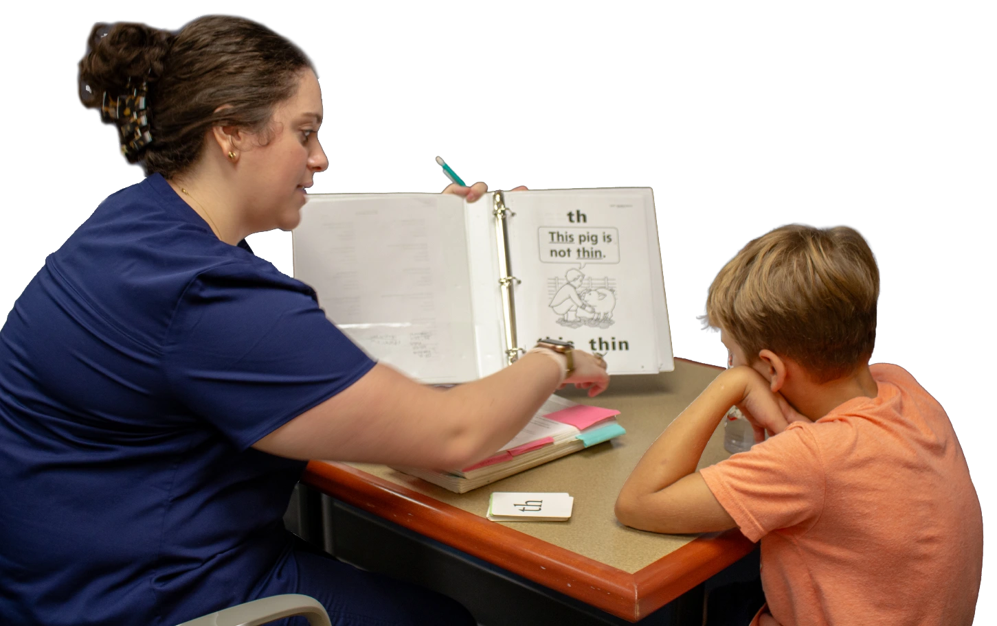 Graduate Student holding an open notebook working with child client on literacy.