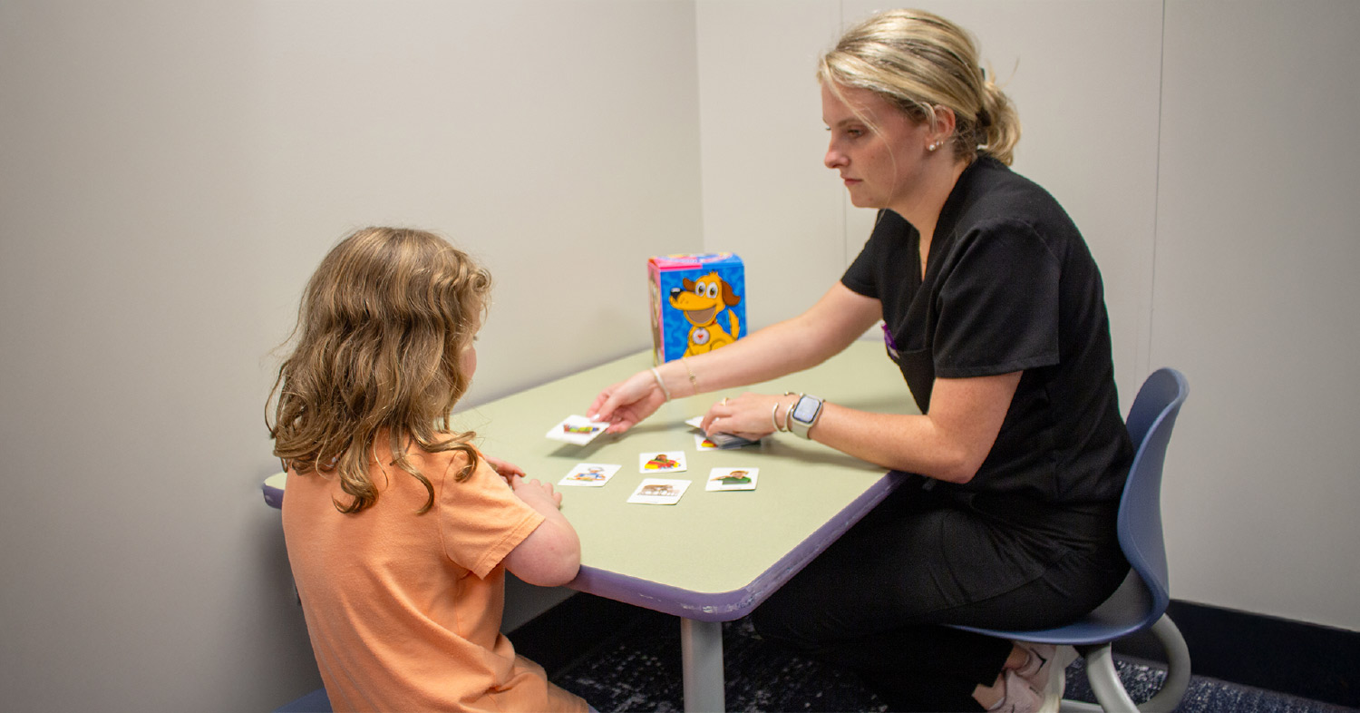 Auburn student playing literacy game with child (girl) client.