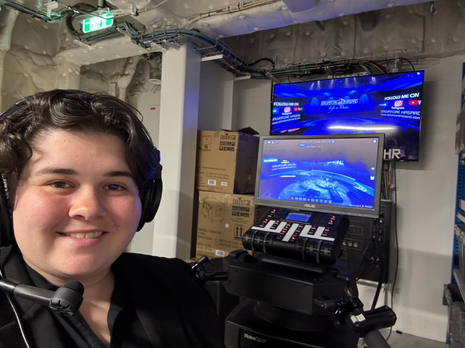 Madison is backstage of ship venue with TV and control panel.